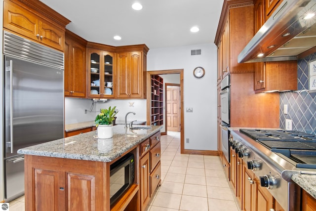 kitchen featuring visible vents, under cabinet range hood, brown cabinets, appliances with stainless steel finishes, and a sink