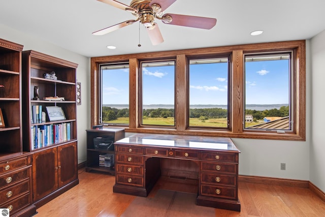 home office featuring baseboards, light wood-style flooring, and a ceiling fan