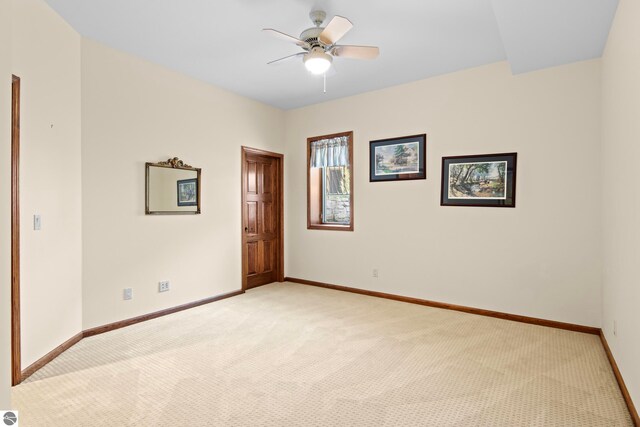 empty room featuring light carpet, a ceiling fan, and baseboards