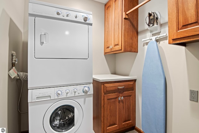 laundry area featuring stacked washer / dryer and cabinet space