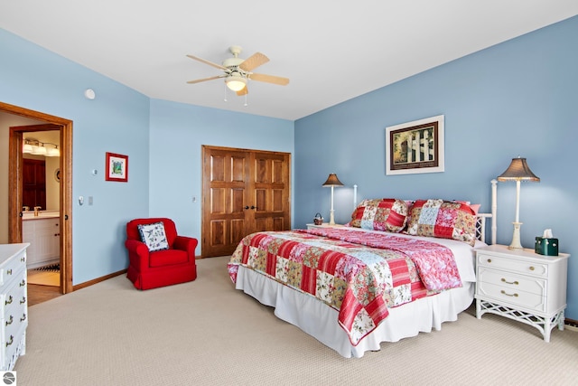 carpeted bedroom featuring a ceiling fan, baseboards, a sink, a closet, and ensuite bathroom