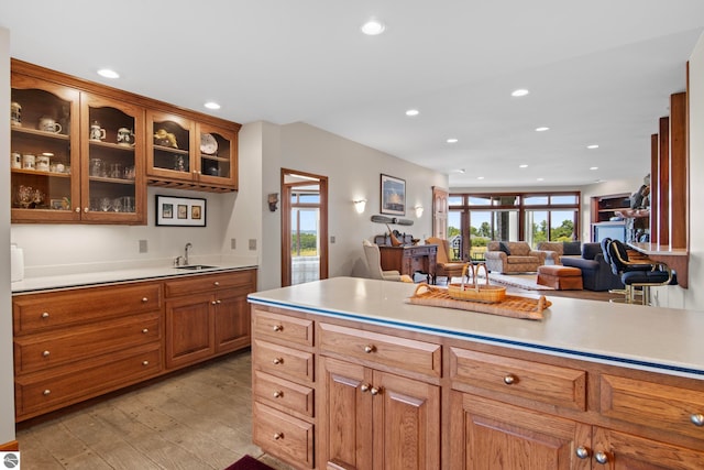 kitchen with recessed lighting, brown cabinetry, light wood-type flooring, and a sink