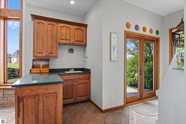 kitchen with dark wood-type flooring, french doors, brown cabinets, and a sink