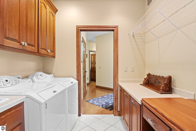 clothes washing area with light tile patterned floors, cabinet space, and washer and dryer