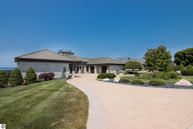 view of front facade with metal roof, stone siding, a front lawn, and a standing seam roof