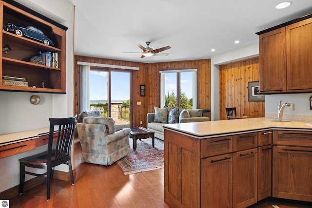 kitchen with a sink, open floor plan, light wood-style floors, a peninsula, and light countertops