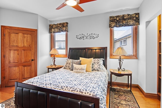 bedroom featuring baseboards, light wood-style floors, and a ceiling fan