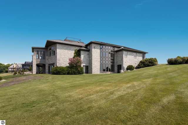 exterior space with stone siding, a lawn, metal roof, and a standing seam roof