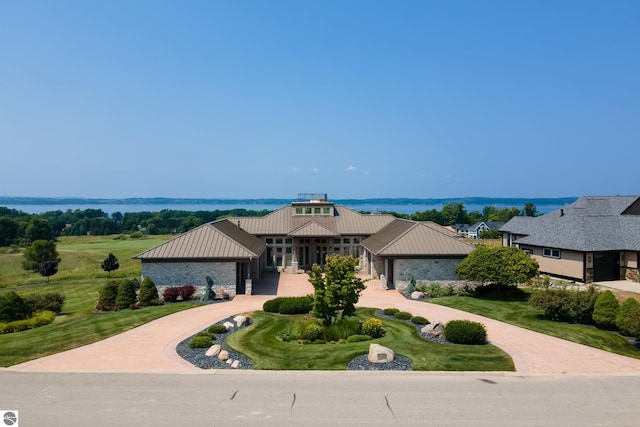 view of front facade featuring stone siding, driveway, metal roof, and a standing seam roof