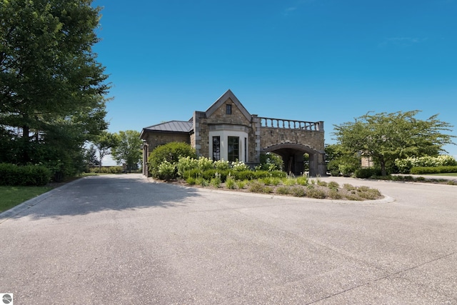 view of front of home featuring stone siding, driveway, metal roof, and a standing seam roof