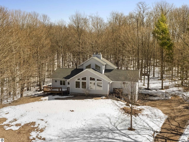 snow covered rear of property with a deck