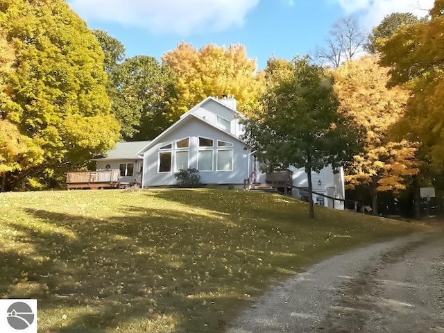 back of property with a lawn, a deck, and a chimney