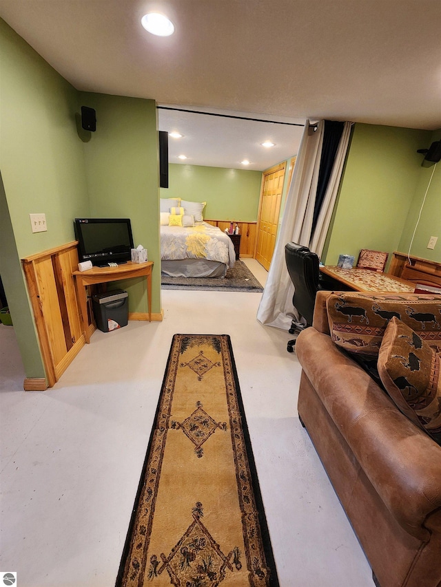 bedroom featuring recessed lighting, a wainscoted wall, wood walls, and finished concrete floors