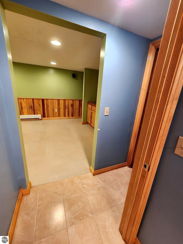 hall with recessed lighting, wood walls, wainscoting, a baseboard radiator, and baseboards