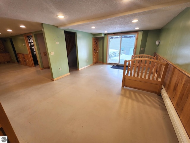 interior space with wooden walls, baseboards, a wainscoted wall, recessed lighting, and a textured ceiling