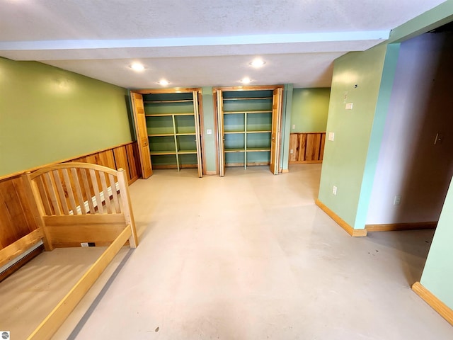 interior space featuring recessed lighting, wainscoting, baseboards, and wooden walls