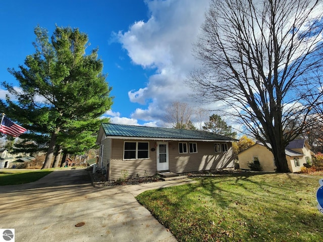 ranch-style house with entry steps, metal roof, a front lawn, and concrete driveway