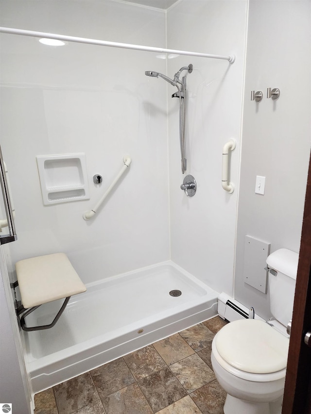 bathroom with baseboard heating, toilet, a shower stall, and stone finish floor