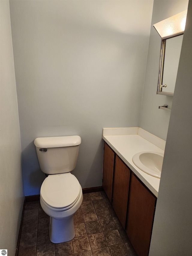 half bath featuring baseboards, toilet, and vanity