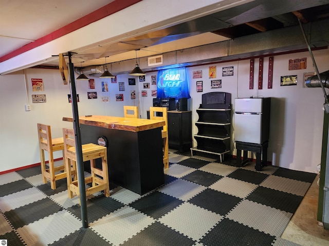 bar with decorative light fixtures, visible vents, a bar, and freestanding refrigerator