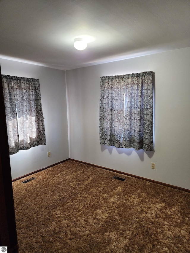 carpeted spare room with baseboards and visible vents