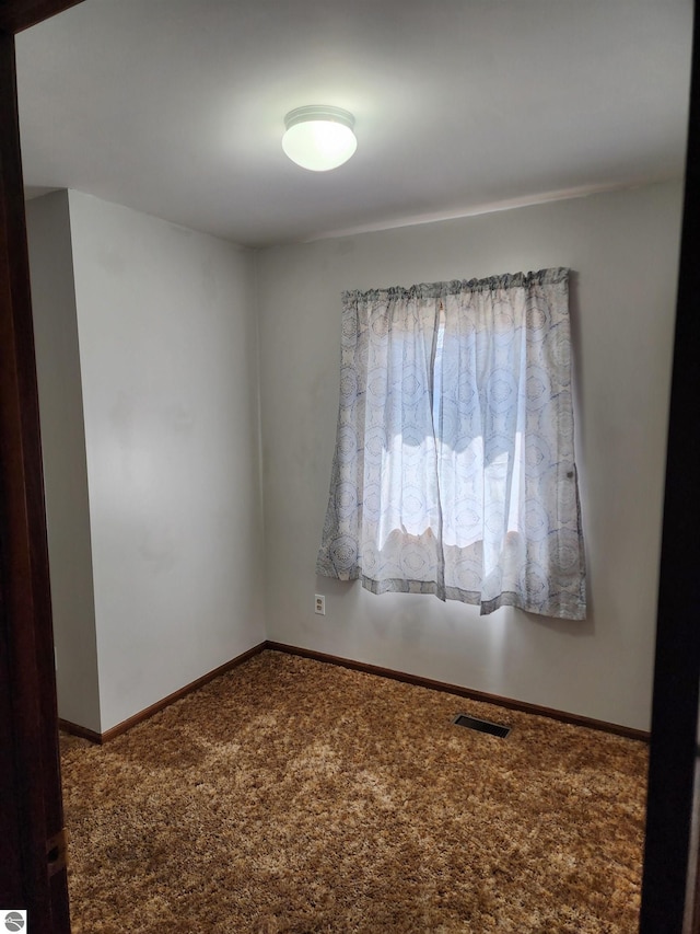 carpeted spare room featuring visible vents and baseboards