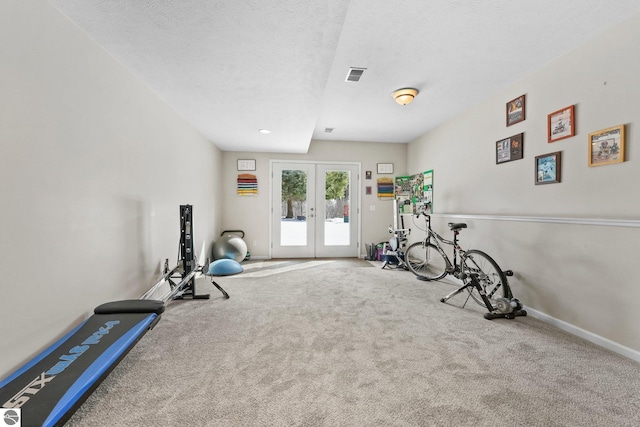 workout area featuring carpet, baseboards, visible vents, french doors, and a textured ceiling