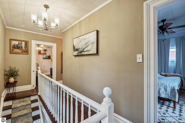 hall with crown molding, a notable chandelier, an upstairs landing, and baseboards