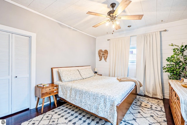 bedroom featuring visible vents, dark wood-type flooring, ceiling fan, ornamental molding, and a closet