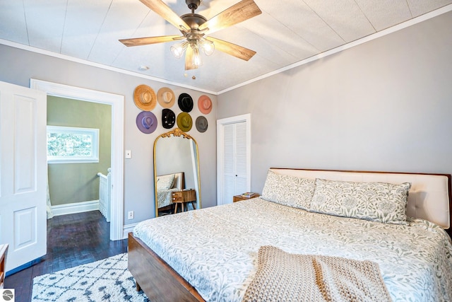 bedroom featuring a closet, wood finished floors, baseboards, and ornamental molding