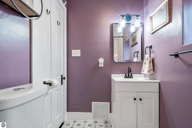 half bathroom with vanity, toilet, baseboards, and visible vents