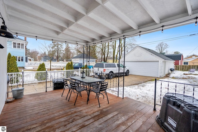 wooden terrace featuring a detached garage, an outbuilding, outdoor dining space, and fence