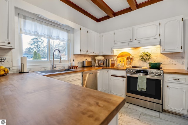 kitchen with under cabinet range hood, appliances with stainless steel finishes, butcher block counters, and a sink