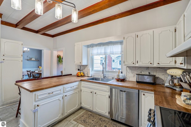 kitchen featuring decorative backsplash, butcher block counters, stainless steel appliances, and a sink