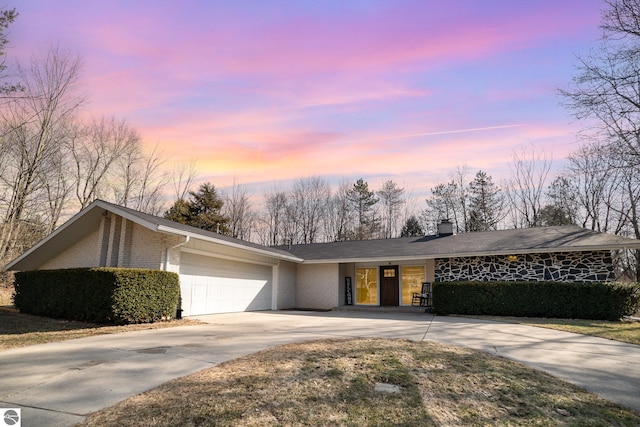 view of front facade with brick siding, an attached garage, concrete driveway, and a chimney