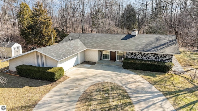 ranch-style house with a garage, brick siding, driveway, and a shingled roof