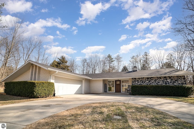 view of front facade with brick siding, driveway, a chimney, and a garage