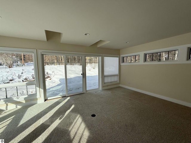 carpeted spare room featuring plenty of natural light and baseboards