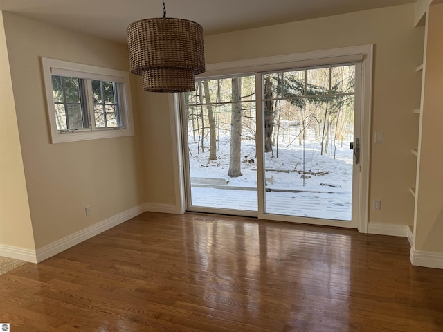 unfurnished dining area with wood finished floors and baseboards