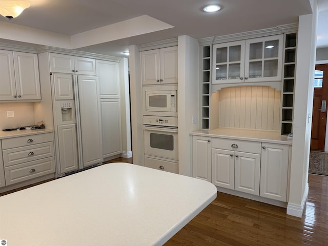 kitchen featuring built in appliances, light countertops, glass insert cabinets, and dark wood-style flooring