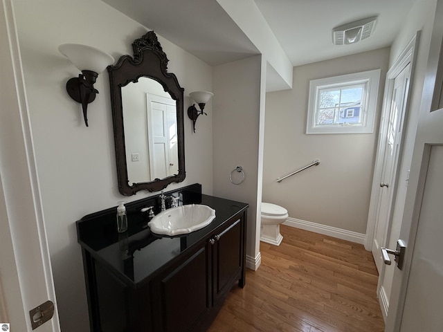 bathroom with visible vents, toilet, wood finished floors, baseboards, and vanity