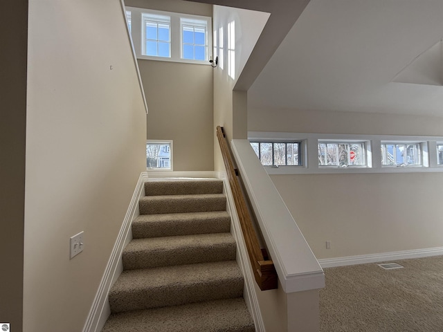 stairs featuring visible vents, baseboards, a high ceiling, and carpet flooring