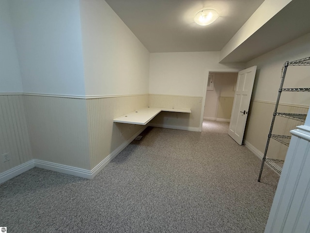 unfurnished office featuring a wainscoted wall and light carpet