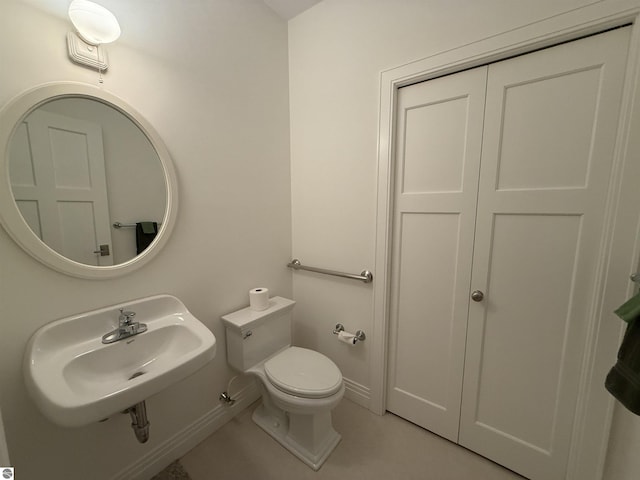 bathroom with tile patterned flooring, toilet, baseboards, and a sink