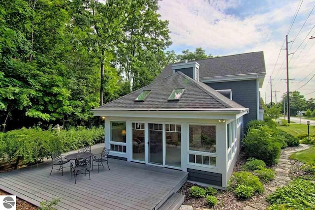 rear view of house featuring a deck, outdoor dining area, and roof with shingles