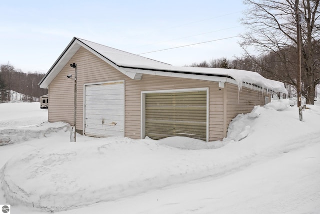 snow covered garage featuring a detached garage