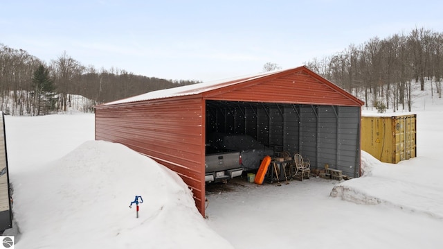 snow covered structure with an outbuilding and a pole building