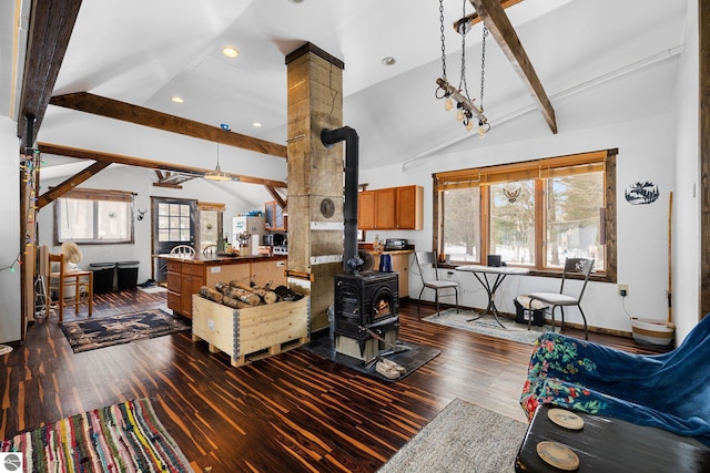 living room featuring dark wood finished floors, vaulted ceiling with beams, a wood stove, and baseboards