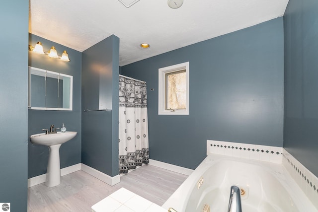 bathroom featuring a shower with curtain, baseboards, a garden tub, and wood finished floors