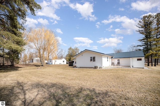 rear view of house featuring a yard and metal roof